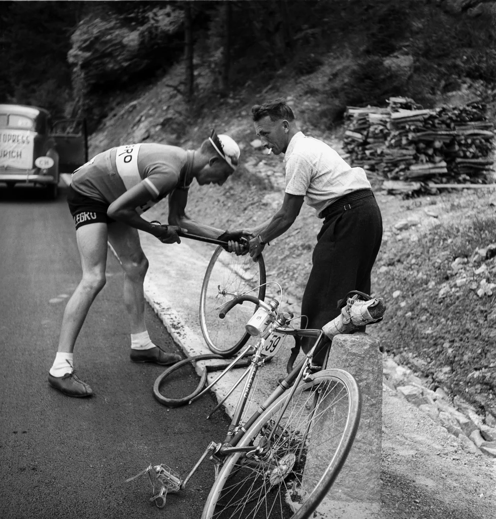 In Quinto in der Leventina fand am Samstag der Prolog der Tour de Suisse 2013 statt. Das Bild stammt vom 8. August 1938. Auf der 3. Etappe von Chur nach Bellinzona hilft ein Zuschauer einem Fahrer, den Reifen zu wechseln. (Aus dem Archiv der Agentur Keystone/Photopress-Archiv/Str)