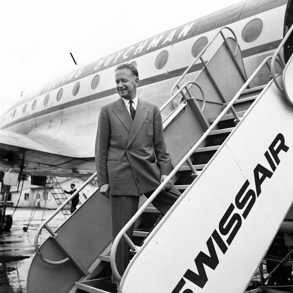 Der Schwede Hammersjöld ist der zweite Uno-Generalsekretär und amtet von 1953 bis zu seinem Tod 1961. Das Bild zeigt ihn am 20. Juli 1956 bei der Ankunft auf dem Genfert Flughafen Cointrin. Hammerskjöld stirbt beim Absturz seines Flugzeuges im heutigen Sambia. Er befand sich auf dem Weg in den Kongo, wo er mit Moïse Tschombé zusammentreffen und im Konflikt um die rohstoffreiche Provinz Katanga vermitteln wollte. Tschombé hatte Katanga für unabhängig erklärt. Die Absturzursache ist immer noch ungeklärt. Spe…