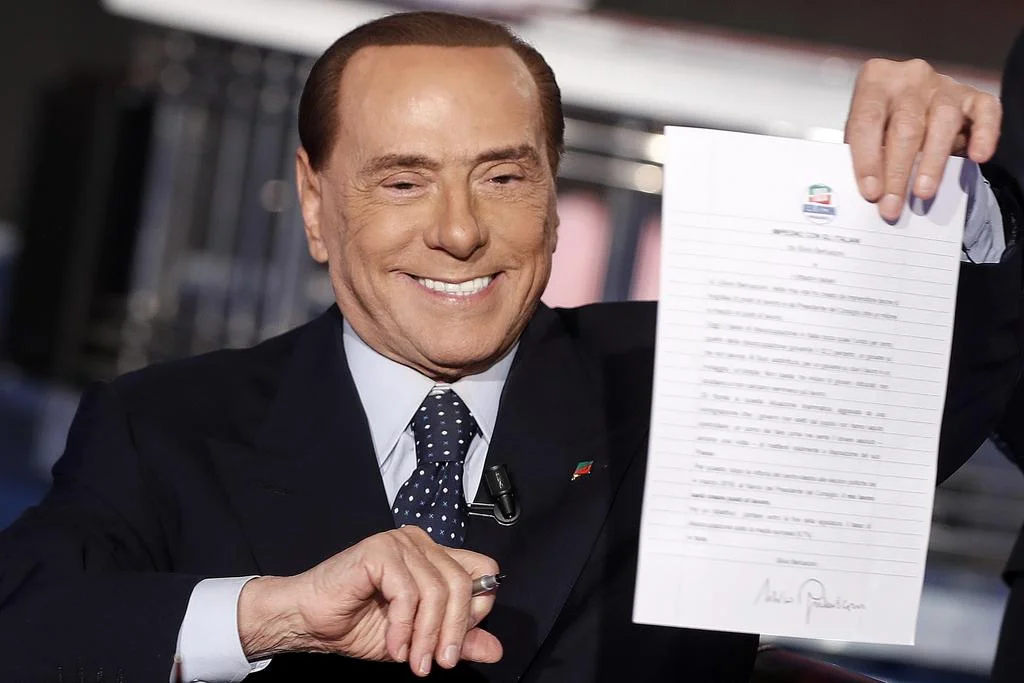 Am Fernsehen zeigt Berlusconi einen von ihm unterschriebenen „Pakt mit Volk“, in dem er verspricht, die italienische Arbeitslosenquote unter den eursopäischen Durchschnitt zu senken. (Foto: Keystone/Ansa/AP/Riccardo Antimiani)