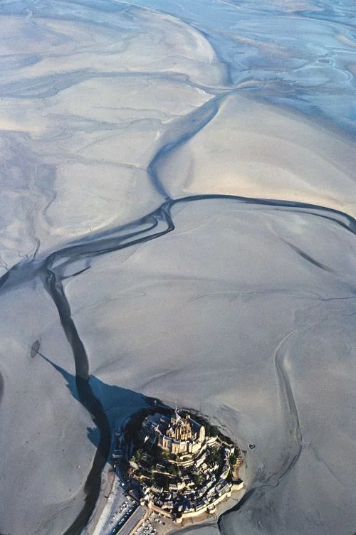 Mont Saint-Michel: "La Merveille"
Benediktinermönche brachten im Spätmittelalter dem Granitkegel vor der normannischen Küste das Beten bei: ab 1204 gaben sie der auf dem Berg bereits bestehenden Abtei aus karolingischer und romanischer Zeit ein neues, himmelstürmendes Aussehen. Den Chor der Abteikirche bauten sie in gotischem Flamboyant mit einem Wald von Fialen um, am Nordabsturz des Bergs türmten sie auf drei Stockwerken Vorratshaus, die Residenz des Almosenpflegers, den Schreibsaal, einen standesgemäss…