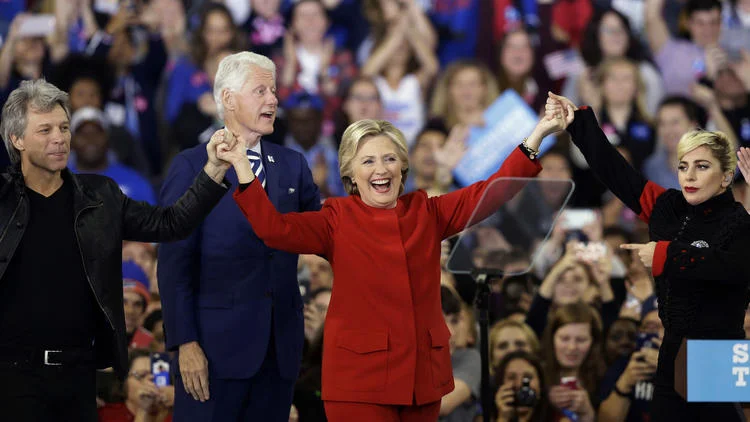 Siegessicher: Die Demokratin an der North Carolina State University in Raleigh (N.C.) wenige Stunden vor Öffnung der Wahllokale. Links Jon Bon Jovi, rechts Lady Gaga, im Hintergrund Bill Clinton (Foto: Keystone/AP/Garry Broome)
