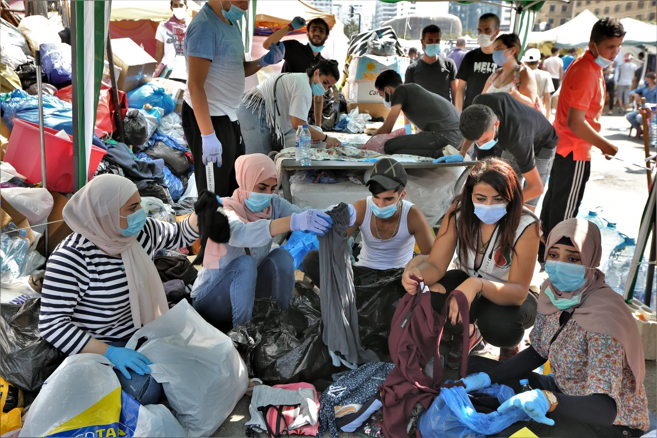 Beirut am 7. August 2020: Freiwillige bringen Familien, deren Häuser durch die Explosion am 4. August zerstört wurden, auf dem Märtyrerplatz im Zentrum Beiruts Lebensmittel und Hilfsgüter. Das libanesische Gesundheitsministerium spricht von mindestens 154 Getöteten und über 5'000 Verletzten. Noch immer wird unter den Trümmern nach Toten gesucht. (Keystone/EPA, Nabil Mounzer)