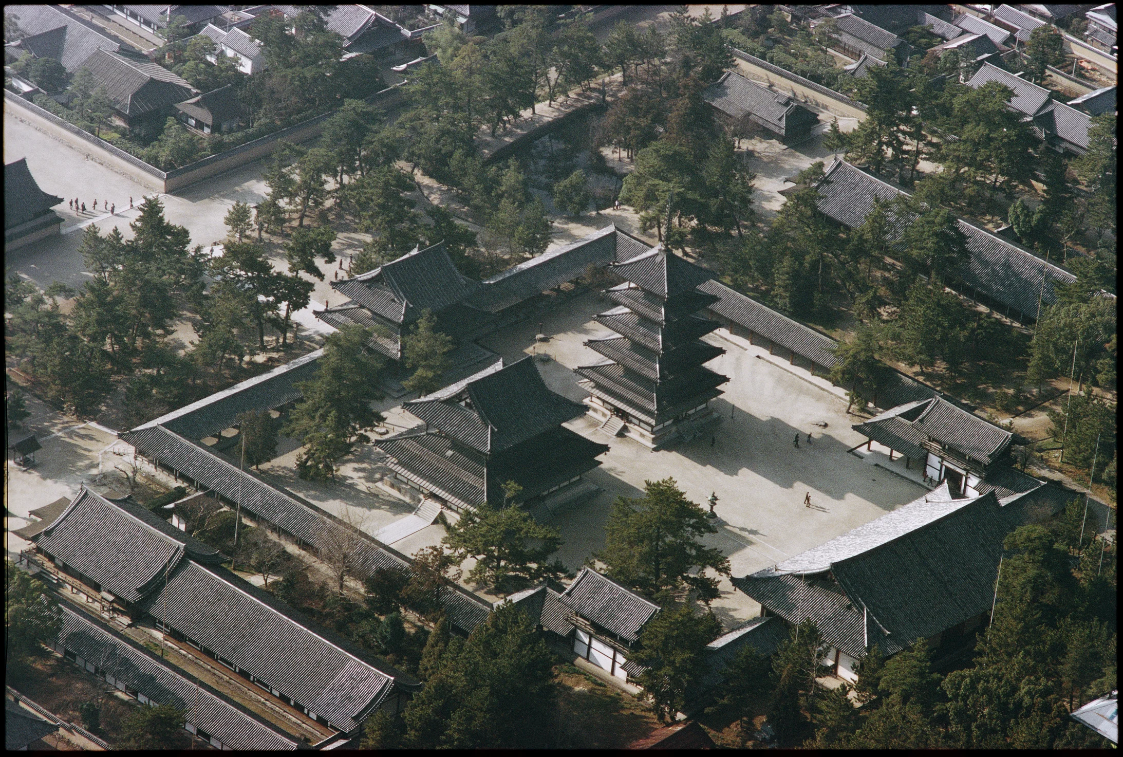  Der Tempelbezirk des Horyu-ji bei Nara, Hauptsitz der budhistischen Shotoku-Sekte, enthält die ältesten Holzbauten Japans und der Welt.

Das Flugbild zeigt den von einem überdachten Wandelgang umgebenen Tempelhof des Westbezirks, mit der fünfstöckigen Pagode (erbaut 607) und der Goldenen Halle (Kondo). Die Tempelanlagen bei und in Nara, unvergleichliche Zeugnisse asiatischer Sakralarchitektur und ein Nonplusultra des Holzbaus, zogen mit erstaunlicher Verspätung ins Pantheon des Welterbes ein: der Horyu-…