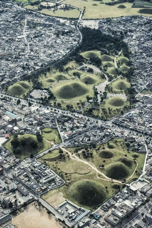 Die Silla-Tumuli - Hügelgräber der Silla-Könige
Scheinbar wahllos im Gelände verstreute Grabhügel prägen die Landschaft Südkoreas. Wirklich wahllos sind die Orte der Bestattungen allerdings nicht. Bevorzugt werden Kämme und Berghänge; Tallagen sind verpönt. Obwohl Reis im Ahnenritual eine Rolle spielt, ist die Nähe der Grabhügel zu Reisfeldern unerwünscht. Gefürchtet wird vermutlich die Bodenfeuchtigkeit, die in der Umgebung der durch Überstauung bewässerten Reisfelder unvermeidlich ist. In einer koreanis…