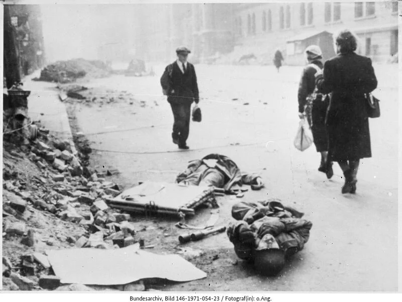 Frankfurt/Main: Passanten gehen an gefallenen, deutschen Soldaten vorbei. (Bild: Deutsches Bundesarchiv, 146-1971-054-23)