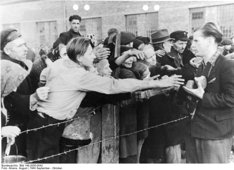 Bildlegende der deutschen Propagandakompanie: „Das erste Stück Brot nach langen Wochen. Gierig strecken sich die Hände der halbverhungerten Warschauer Zivilbevölkerung dem Brot entgegen, das die deutsche Führung durch das polnische Rote Kreuz verteilen lässt.“ (Bild: Deutsches Bundesarchiv,  146-2005-0042, Fotograf: Augustin Ahrens, September/Oktober 1944) 