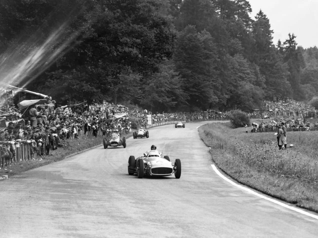 Den Grossen Preis der Schweiz gewinnt der Argentinier Juan Manuel Fangio auf Mercedes-Benz (hier im Bild vorne). Die kurvenreiche Strecke war 7,28 Kilometer lang. 14 Grand-Prix-Rennen hatten seit 1934 im Bremgartnerwald stattgefunden. Zwischen 1947 und 1954 starben neun Menschen. Nach dem Unfall in Le Mans am 11. Juni 1955, bei dem 84 Menschen ums Leben kamen, wurden Motorsportrennen in der Schweiz verboten. (Foto: Keystone/Photopress-Archiv/Hermann Schmdidli/Kraft)